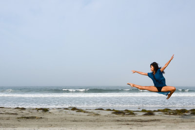 fine art photographer David Lee Black with color photograph of model ballet dancer leaping next to Atlantic ocean beach with sky, waves, and sky. 