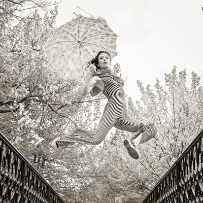 Fine art photographer David Lee Black 's black and white photograph of model with umbrella and converse sneakers jumping at Roger Williams Park, Providence, Rhode Island. 